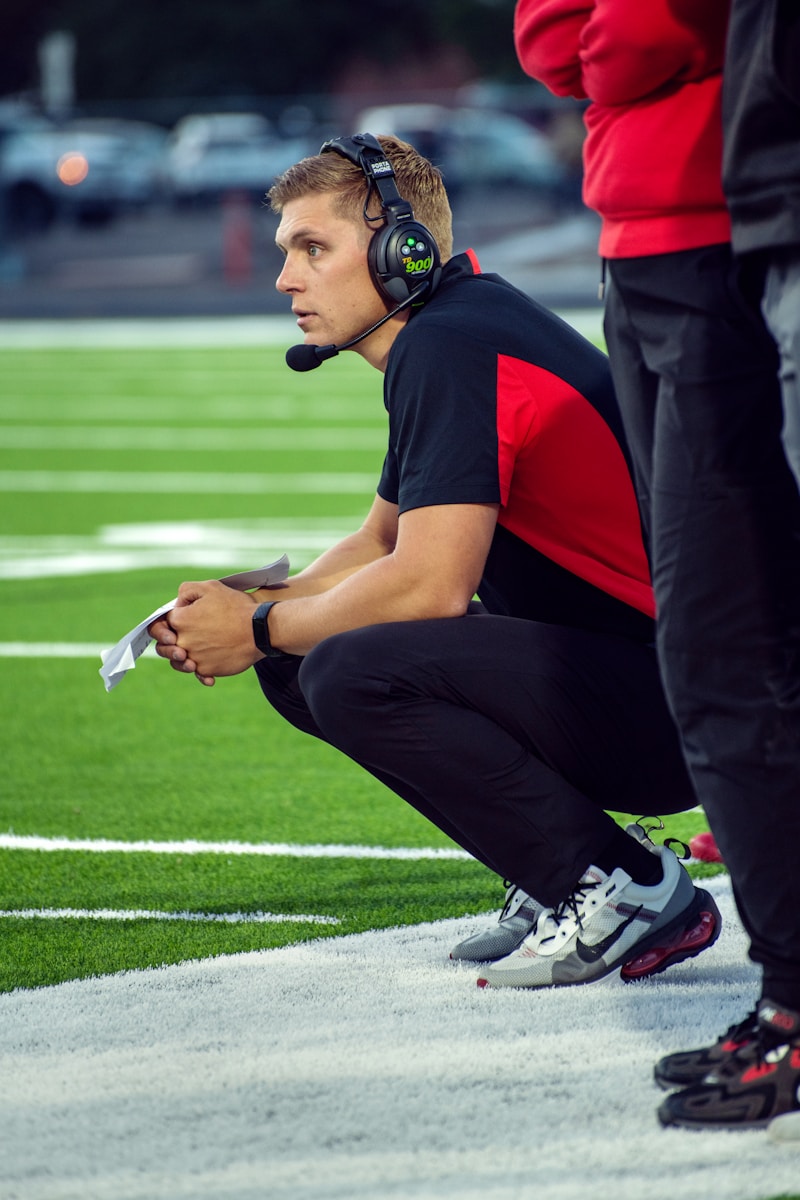 Photo by Tim Mossholder a person wearing headphones and kneeling on a football field